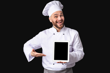 Excited Male Chef Showing Digital Tablet Screen Posing, Black Background