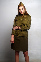 A girl soldier in camouflage clothing poses in a Studio
