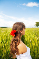 Beautiful girl is standing with her back in a white dress in a wheat field