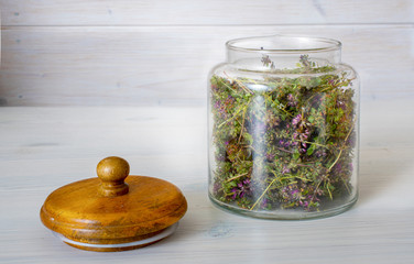 Jar with thyme on a white wooden shelf