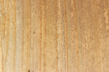 The surface of the cliff of yellow and brown sandstone on the seashore, weathered and faded in the sun.