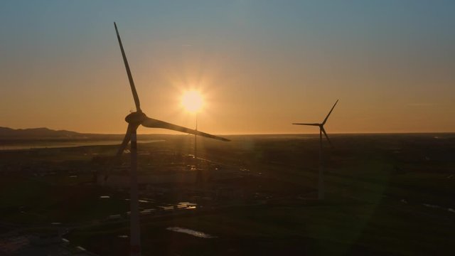 Sagome di pale eoliche che girano al tramonto in citt&agrave;. Sfondo anonimo del cielo.