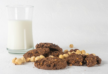 Chocolate cookies for breakfast with mint and hazelnut and a glass of milk on a gray table