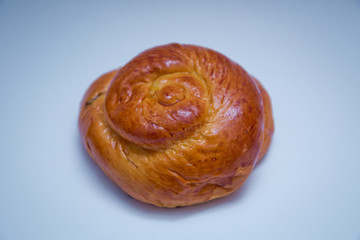 Freshly baked sweet bun with raisins isolated on white background, top view . Freshly baked sweet bun with raisins isolated on white background, top view . Fresh bake cinnamon roll with a cherry .