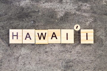 Hawaii word written on wood block, on gray concrete background. Top view.