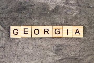 Georgia word written on wood block, on gray concrete background. Top view.
