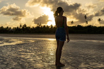 Sunset in a topical beach with the back of a woman  (Alagoas, Brazil)