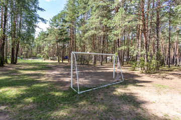 swing and horizontal bars on playground and football court in pine forest