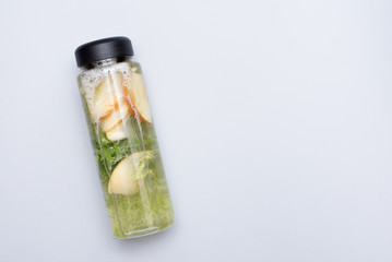 Detox Infused Water with apple, Lime and Mint in Sports Bottle, with cut pieces of cucumber on gray background, copy space