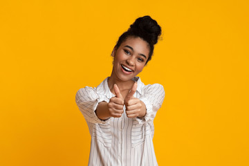 Positive afro girl showing thumbs up at camera and smiling