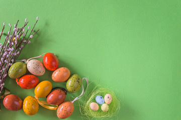 Easter and spring still life. Various easter eggs and bouquet of willow twigs on bright green background. Space for text, flat lay