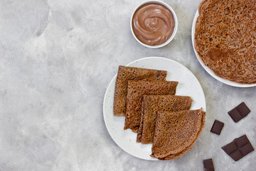 Sweet breakfast or dessert: chocolate crepes (thin pancakes) and chocolate cream. Copy space, top view.