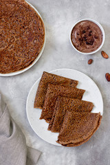 Sweet breakfast or dessert: chocolate crepes (thin pancakes) and chocolate cream. Top view.