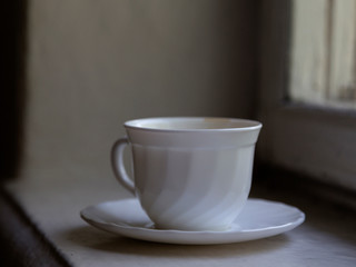 White cup is located on a windowsill.