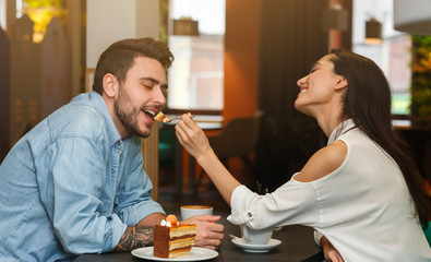 Loving Couple Feeding Each Other On Romantic Date In Cafe