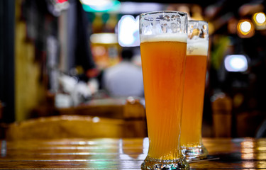 two glass of light beer stands on a table in a bar or pub