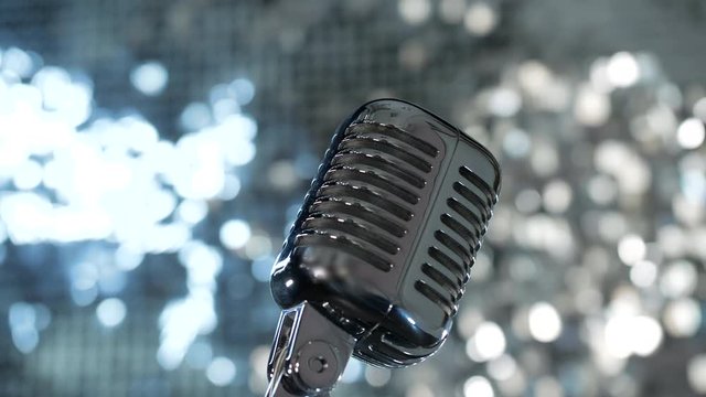 Concert vintage microphone on nightclub stage on silver shiny background. Object for musical performance, occupation lifestyle on entertainment event. Audio equipment on music record speak studio song
