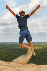 Lebensfreude: Ein Junge springt auf einer Sanddüne in die Luft.