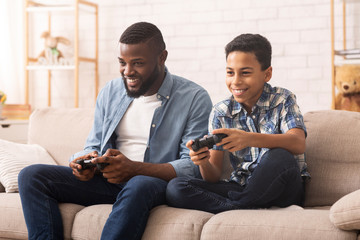 Excited Black Boy Playing Video Games With Dad At Home