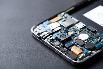 The inside of the smartphone's motherboard and tools lay on the white table. the concept of computer hardware, mobile phone, electronic, repairing, upgrade and technology.