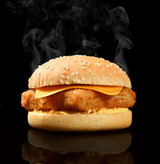 Tasty burger with fish fillet and cheese hot with steam smoke on black