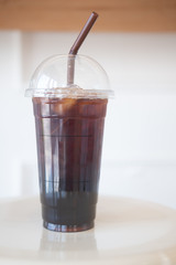 Long black coffee with ice in tall plastic glass
