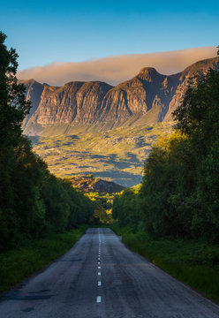 The mountain range of the Knockan Crag National Nature Reserve at sunset, seen from the two-lane highway of A385 near Elphin, Lairg, Scotland. 