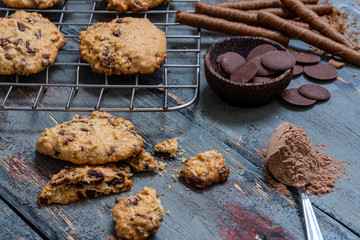 Chocolate cookies, on rustic wood next to cocoa in different forms