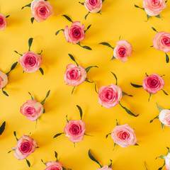 Flat lay pink rose flower buds and leaves pattern on yellow background. Top view floral texture.
