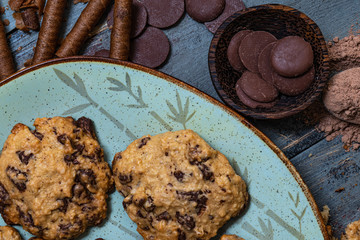 Chocolate cookies, on rustic wood next to cocoa in different forms