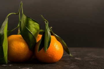 Orange tangerines on a black background. There is a place for text.