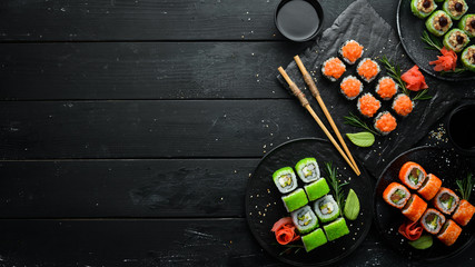 Set of colored sushi in black plates. Japanese food. Top view. Free space for your text.