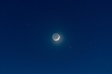 Waxing crescent moon, earthshine and starry night sky
