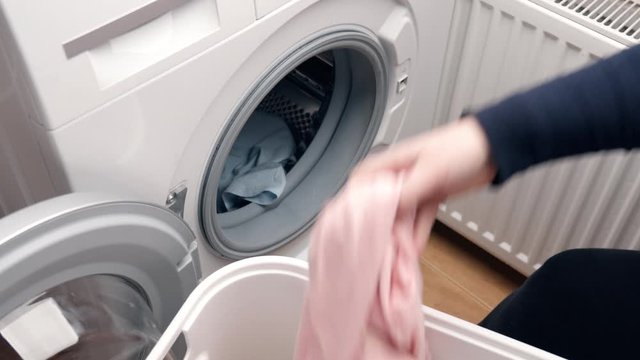 Housewife loads clothes from Laundry basket into a washing machine. Hygiene at home concept. Work in the bathroom.