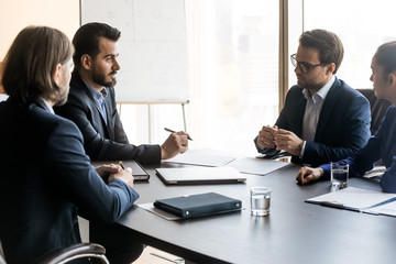 Confident businessman discuss project on flipchart background sit at table.