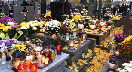 Herbstlicher Friedhof mit Blumenschmuck, Kerzen und gelbem Laub