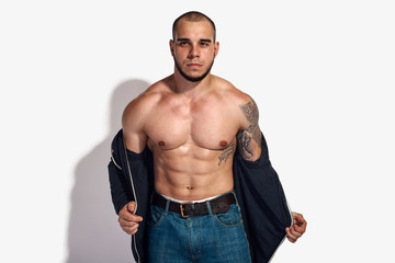 Athletic strong man taking off clothes and showing muscular torso