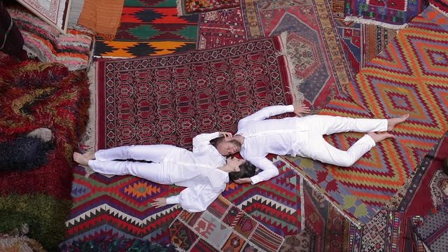 Young Happy Couple is Lying Down on the Floor and Laughing. Man Hugs the Girl. Cozy Colorful Carpet Room in Cappadocia