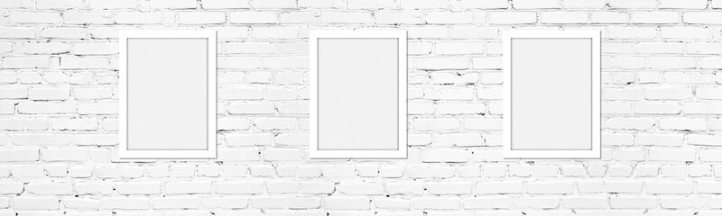 Blank white photo frames on light whitewashed brick wall