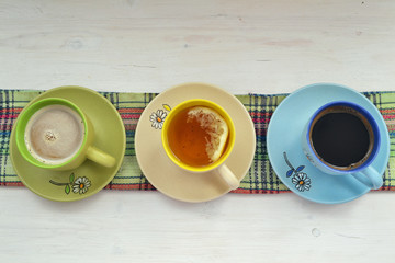 cup of coffee, tea and cacao or cappuccino in colorful cups