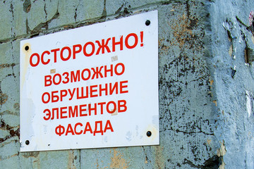 Empty plate on an old brick wall, restoration of an old building. Russian text carefully collapse of the facade
