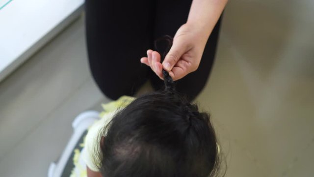 mum hair tie her daughter at home.