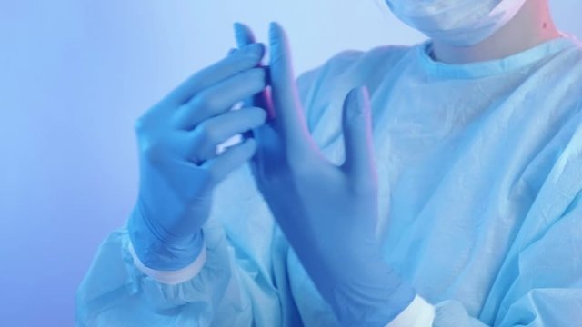 Doctor checking blue protective gloves for proper fit