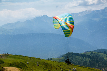 A tourist with an instructor flies a paraglider on the background of a beautiful mountain...