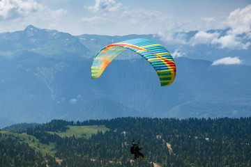 A tourist with an instructor flies a paraglider on the background of a beautiful mountain...