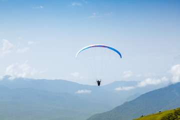 A tourist with an instructor flies a paraglider on the background of a beautiful mountain landscape. Extreme sports in the mountains.