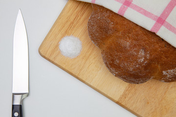 Large loaf of bread with bread cutter knife, on the white table