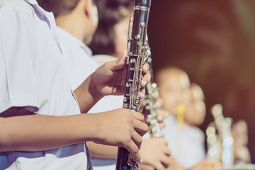 Fototapeta premium Male student with friends blow the clarinet with the band for performance on stage at night.