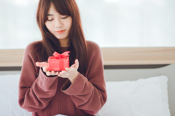 Woman surprised looking at gift ,Young woman receiving a surprise gift box from her boyfriend at home.