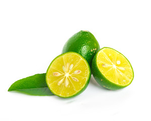 Single raw Asian lime with two half cuts and green leaves isolated on white